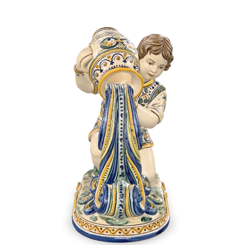 Giovane in maiolica che versa acqua da una grande anfora sulla spalla: il getto scende fino alla base come un’onda scolpita, in cobalto e zafferano.