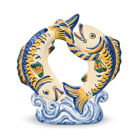 Due pesci in maiolica disposti in cerchio, testa contro coda, con le scaglie dipinte in zafferano e cobalto, su una base a forma d’onda.