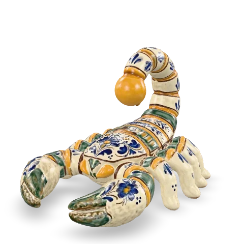 Scorpione in maiolica con le chele in avanti e la coda a segmenti alzata sul dorso, la punta zafferano, smalto bianco decorato in cobalto e ramina.